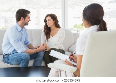 Reconciled couple smiling at each other in the therapist office