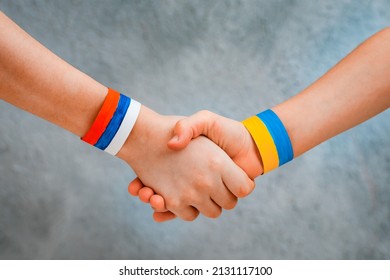 Reconciliation Concept And Handshake. Children's Hands With The Drawing Of A Flag Of Ukraine And Russia