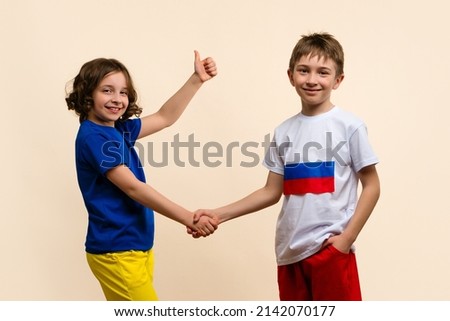 Reconciliation. Friendship fraternal peoples. Children Girl and Boy in outfits in colors flags of Russia and Ukraine shake hands. Child shows thumb up sign ok. Concept Successful truce negotiations. 