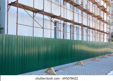 Reconstruction Building With External Insulation And Plaster And With Using Of Scaffolding. Temporary Metal Fence Around The Construction Site