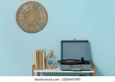 Record player with disk and home decor on shelving unit near blue wall in room