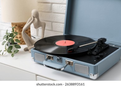 Record player with disk on commode near white brick wall in room