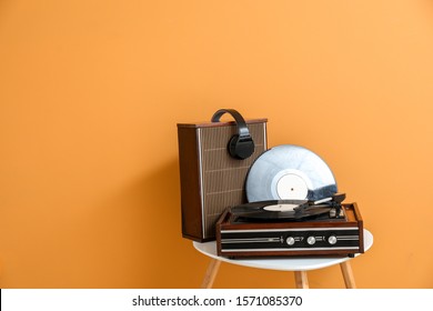 Record player, speaker, headphones and vinyl disk on table near color wall