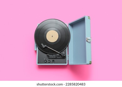 Record player with vinyl disk on pink background