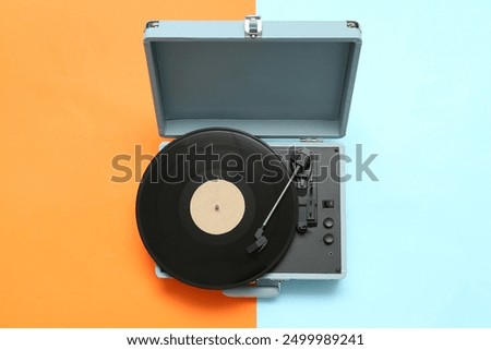 Record player with vinyl disk on color background