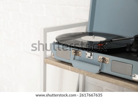 Record player with vinyl disk on wooden shelf