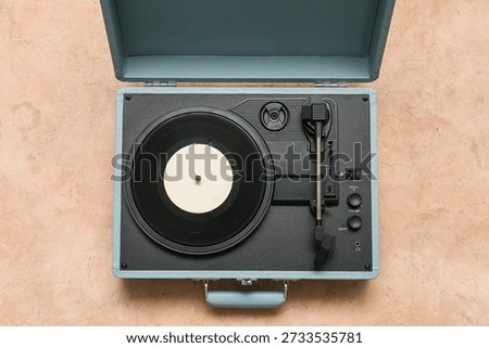 Record player with vinyl disk on beige background