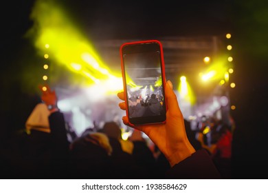 Recording a concert with mobile phone, silhouette of hands with smartphone.