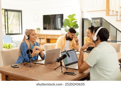 Recording podcast, group of young friends using laptops and microphones indoors. Podcasting, technology, collaboration, teamwork, audio, digital - Powered by Shutterstock