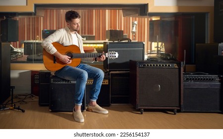 Recording studio, acoustic and man playing the guitar for music production or practicing for a performance. Artist, guitarist and guy strumming the strings of a musical instrument for a sound track.