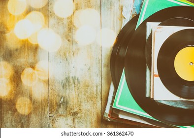 records stack over wooden table and vintage light leaks. filtered image
