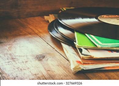 records stack with record on top over wooden table. vintage filtered
