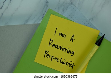 I am a Recovering Perfectionist write on sticky note isolated on Wooden Table. Selective focus on I am a Recovering Perfectionist text