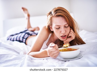Recovering Woman In Bed Eating Chicken Soup While Sick