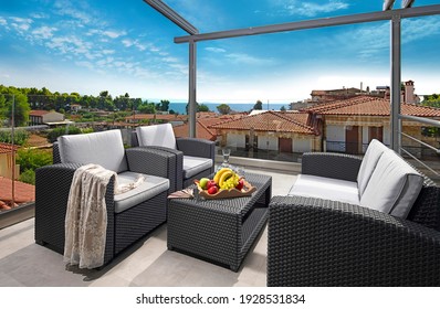 Recreation concept panorama of modern patio with wicker grey rattan furniture. Contemporary armchairs, couch, table on roof top terrace of luxury sea view resort in old European city
