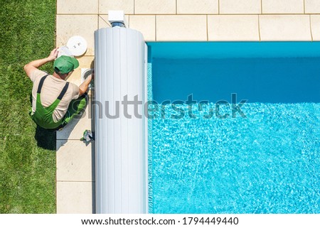 Recreation Industry Theme. Residential Outdoor Swimming Pool Skimmer Filter Cleaning by Professional Caucasian Pool Technician. Aerial View.