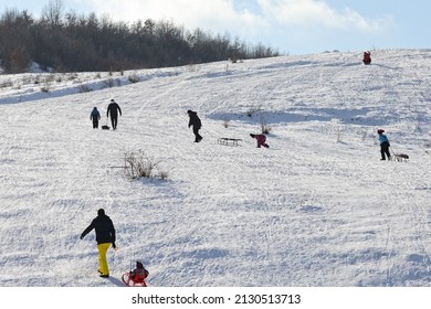 Recreation people and children go sledding, skiing on the sunny, snowy hillside on the weekends in winter. Color landscape photo. Illustration of winter sports, holidays and tourism. - Powered by Shutterstock
