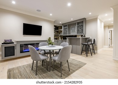 Recreation room and bar with wine rack popcorn machine large screen tv theater in grey tones and round dining table sofa and light tone hardwood floors - Shutterstock ID 2154282935