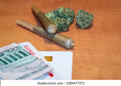 Recreational Cannabis Legalization In Illinois. Two Marijuana Joints Are Displayed With An Illinois ID Card And Money On A Table.