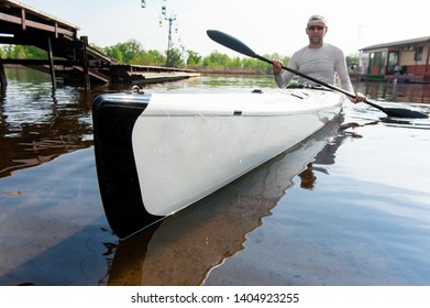 Recreational fisherman. Low angle ?lose up photo of serious adult sports guy sitting in kayak and holding paddle. Focus on bow of the boat - Powered by Shutterstock