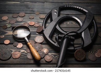 Recreational Metal Detector And Ancient Coins On The Wooden Table Background. Treasure Hunting Concept Background.