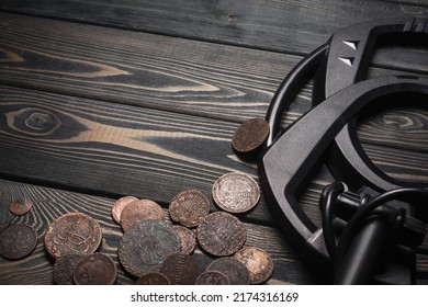 Recreational Metal Detector And Ancient Coins On The Wooden Table Background With Copy Space. Treasure Hunting Concept Background.