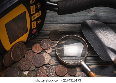 Recreational Metal Detector And Ancient Coins On The Wooden Table Background. Treasure Hunting Concept Background.