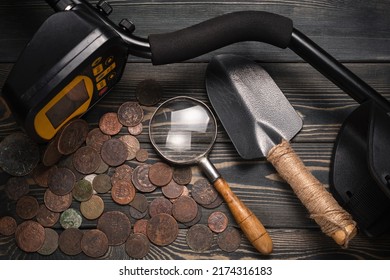 Recreational Metal Detector And Ancient Coins On The Wooden Table Background. Treasure Hunting Concept Background.