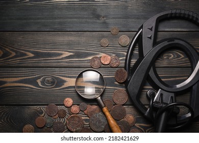 Recreational Metal Detector And Ancient Coins On The Wooden Table Background With Copy Space. Treasure Hunting Concept Background.