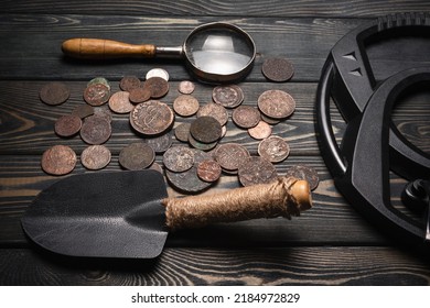 Recreational Metal Detector And Ancient Coins On The Wooden Table Background. Treasure Hunting Concept Background.