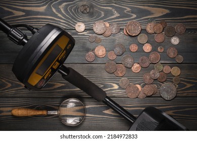 Recreational Metal Detector And Ancient Coins On The Wooden Table Background Top View.