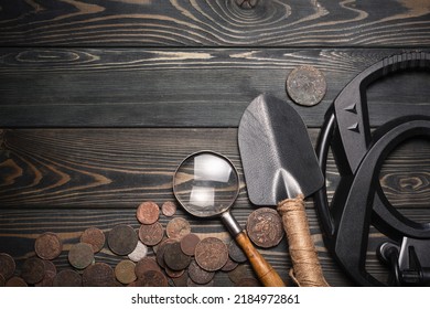 Recreational Metal Detector And Ancient Coins On The Wooden Table Background With Copy Space. Treasure Hunting Concept Background.