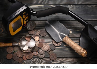 Recreational Metal Detector And Ancient Coins On The Wooden Table Background. Treasure Hunting Concept Background.