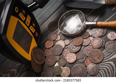 Recreational Metal Detector And Ancient Coins On The Wooden Table Background. Treasure Hunting Concept Background.