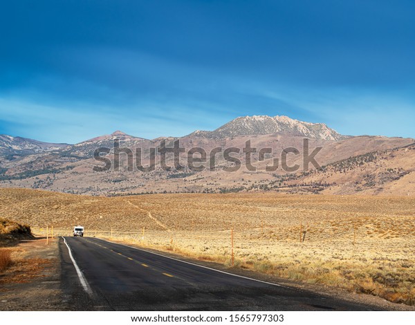 Recreational vehicle towing a car\
through the mountains of the Eastern Sierras in Northern\
California.