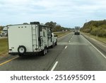 Recreational vehicle towing a trailer on a busy highway, depicting the lifestyle of travel and adventure across scenic roadways.