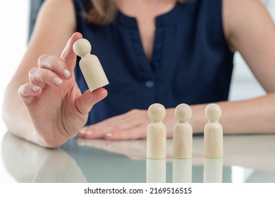 Recruiting employees. Wooden man in front of recruiter. Concept of personnel selection for company. Recruitment for business. Girl chooses one candidate from several. Recruiter interview metaphor - Shutterstock ID 2169516515