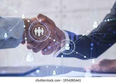 Recruitment concept to hiring of a new talented specialists for international company. Handshake to sign in of employment agreement. Social media hologram icons over the table with documents.