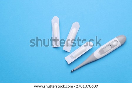 Rectal suppositories and thermometer on a blue background