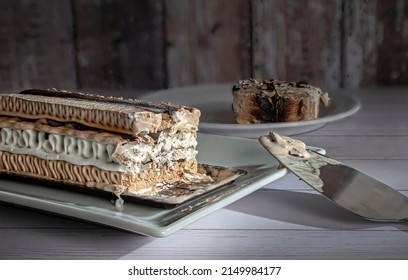 A Rectangle Shape Coffee Moka Ice Cream Cake On A White Plate With A Slice Served In The Background