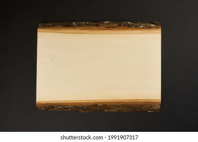 Rectangle slab of wood with bark on back background.                                  