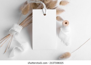 Rectangle white tag mockup on a white background with cotton string and boho decoration, dry plants, element for packing. Label product bohemian mockup copy space for text and natural eco design