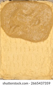 A rectangular baking pan with a partially baked pie crust, with cooked apple filling spread over approximately half of its surface