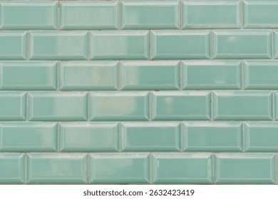 Rectangular beveled subway tiles creating a seamless pattern and textured surface in a soothing light green color