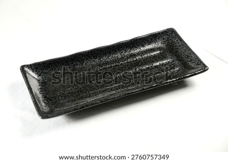Rectangular black ceramic serving platter features a textured surface design, ideal for serving appetizers or desserts in a modern dining setting