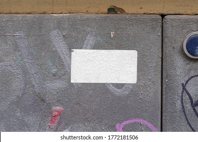 Rectangular blank sticker mockup on the street glued to the wall. White textured label template.
