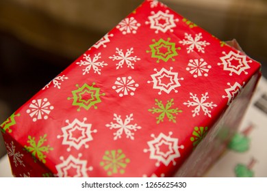 Rectangular box wrapped in red, white, and green wrapping paper.