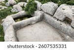A rectangular collection basin and crushing trough carved into the rock, forming an ancient wine press workshop, located in the ruins of Sakizlik, in the Saglikli neighborhood of Tarsus, Mersin.