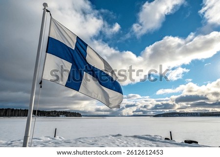 A rectangular Finnish flag with a white background and blue Nordic cross, fluttering above a lake under a bright sky