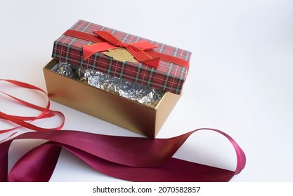A rectangular gift box with a red bow and a Scottish cage. A gift for Christmas in a beautiful package. Christmas Tree garland